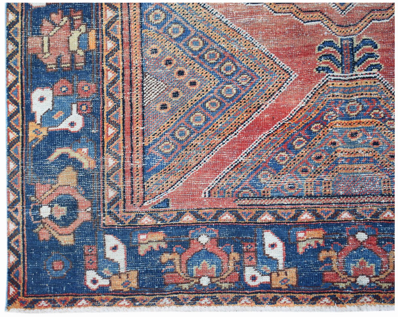 A handwoven vintage Persian rug featuring geometric patterns in red, blue, and orange tones.
