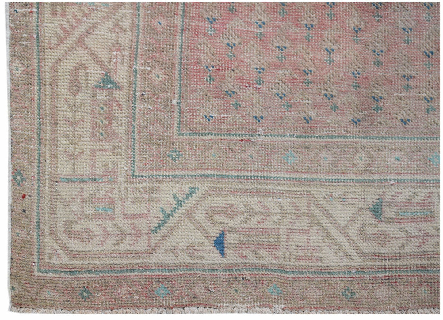 A vintage handwoven Persian rug featuring a faded pink field with blue floral accents and borders.
