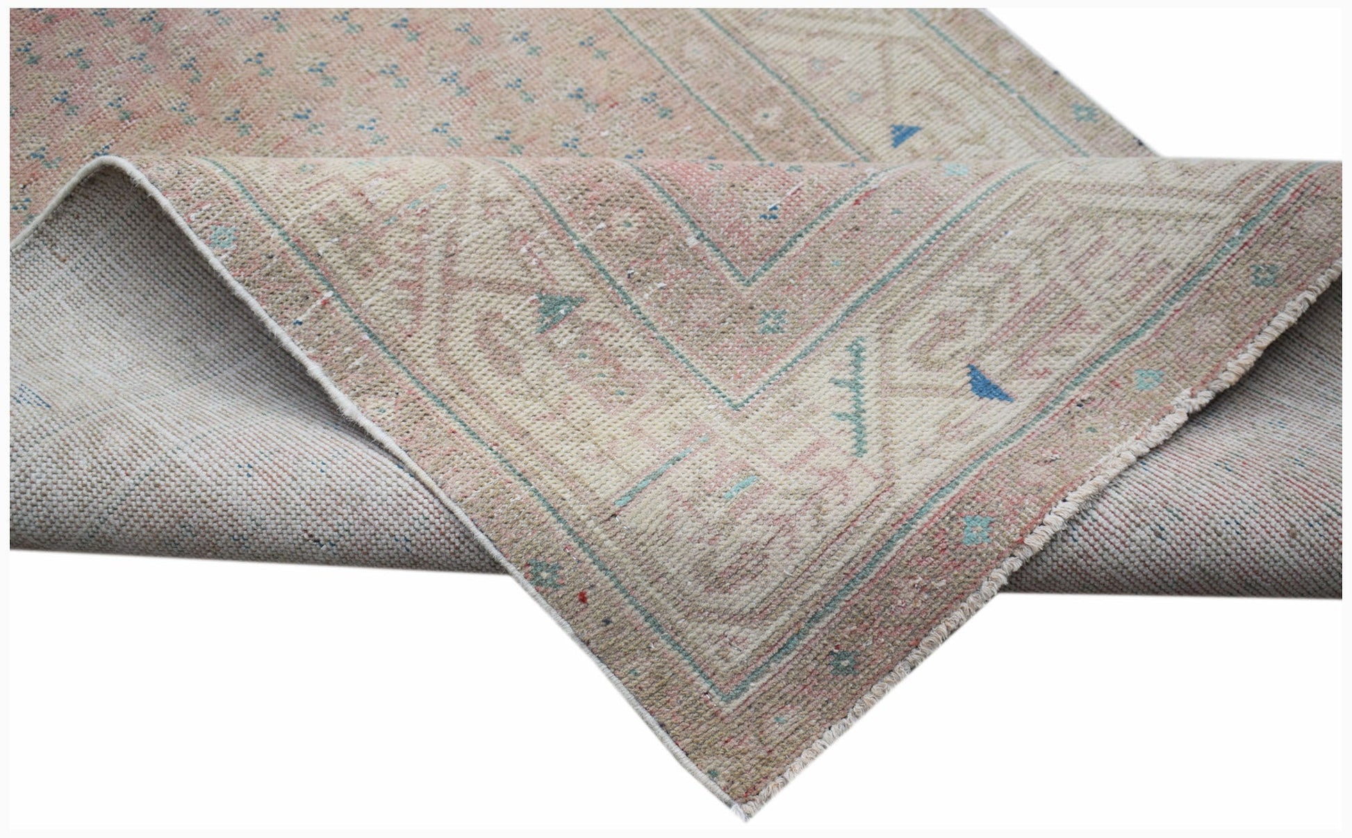 A handwoven vintage Persian rug featuring a faded pink and beige pattern with blue accents.