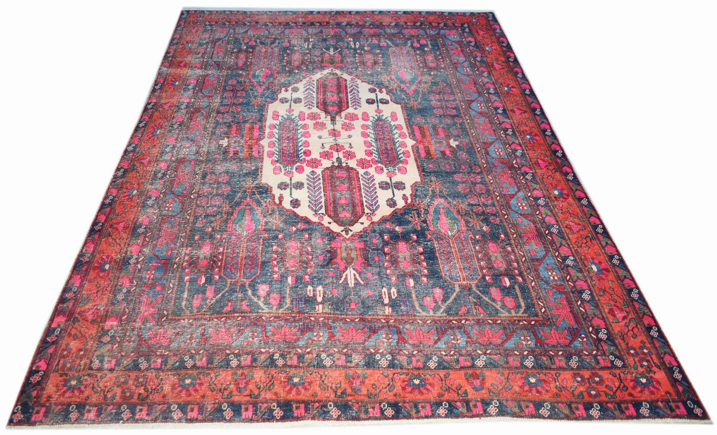 A handwoven vintage Persian rug featuring a central cream medallion on a blue and red floral field.