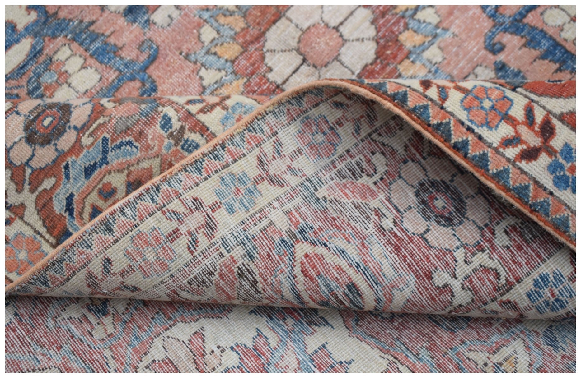A vintage Persian rug with a floral pattern in faded red, blue, and cream tones.