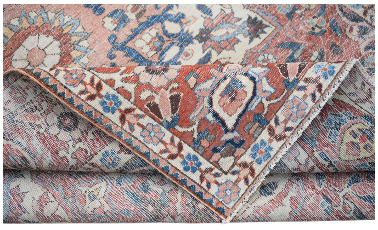 A handwoven vintage Persian rug featuring a floral pattern in faded red, blue, and cream tones.