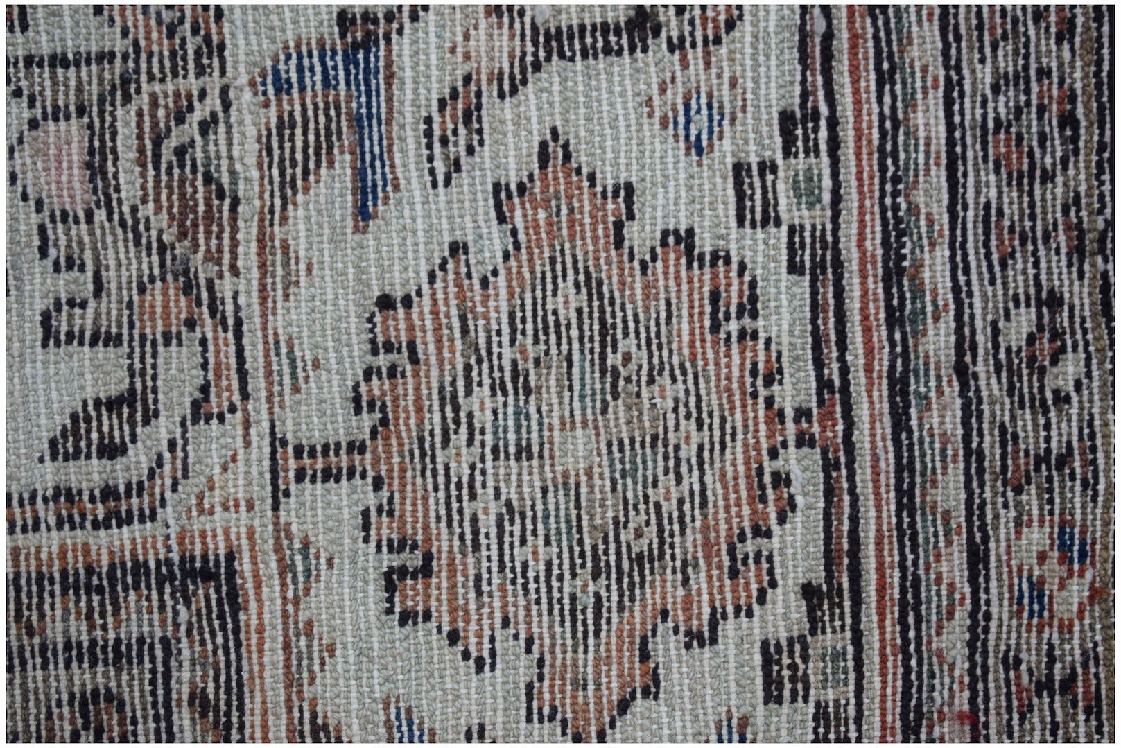 A close-up of a vintage handwoven Persian rug featuring intricate floral patterns in muted tones.