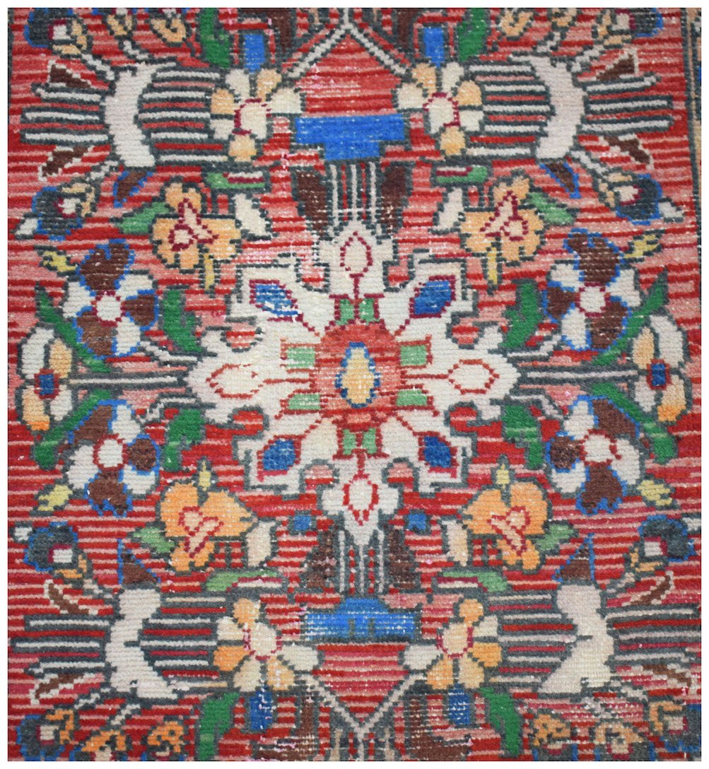A vintage Persian Sarouk runner featuring a floral medallion pattern on a red wool field.