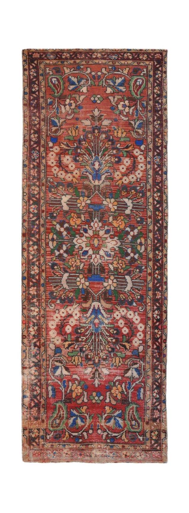 A handwoven vintage Persian Sarouk runner featuring a floral pattern on a red wool field.