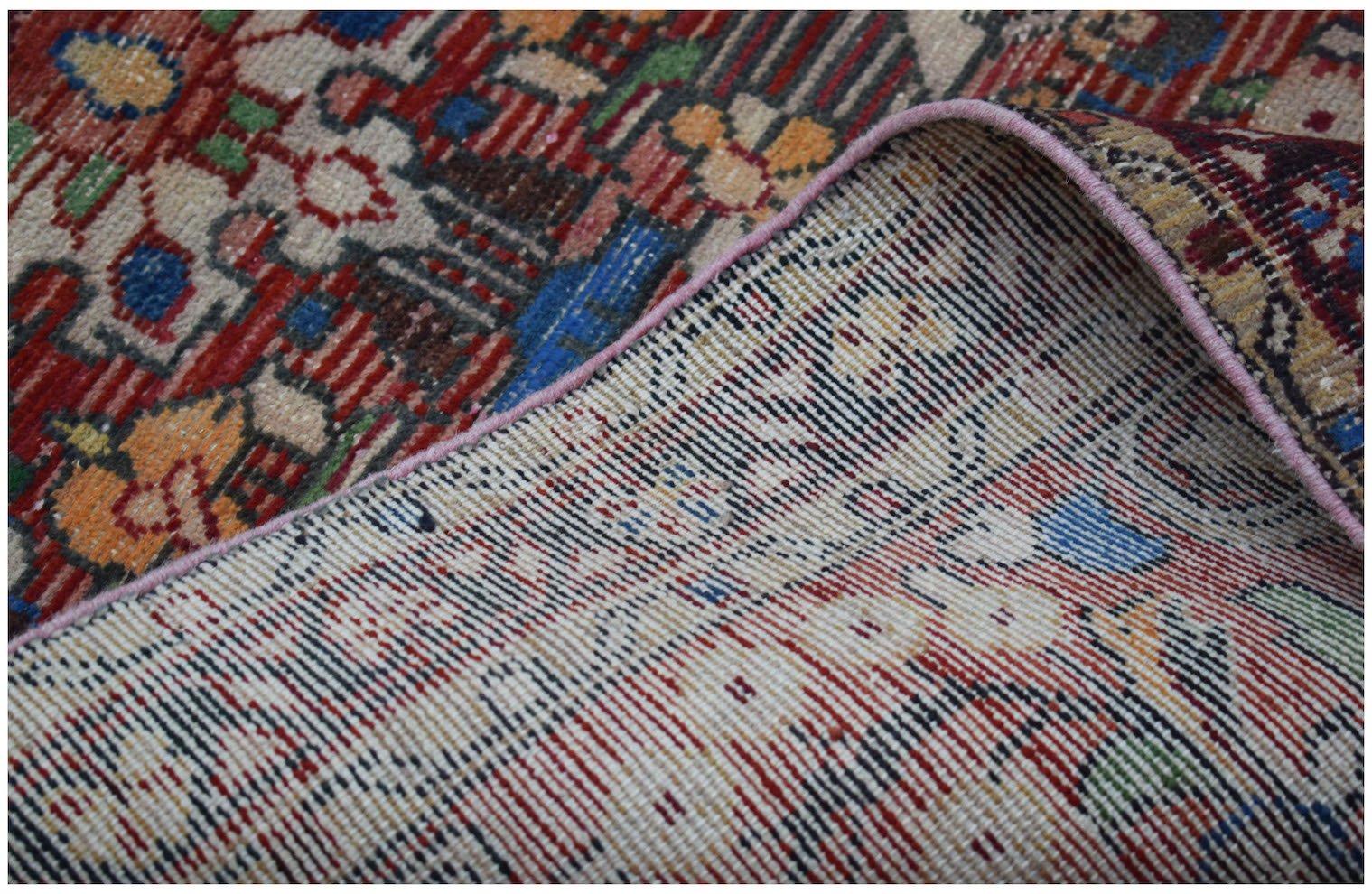 A corner of a vintage Persian Sarouk runner is folded back to reveal its handwoven cotton base.