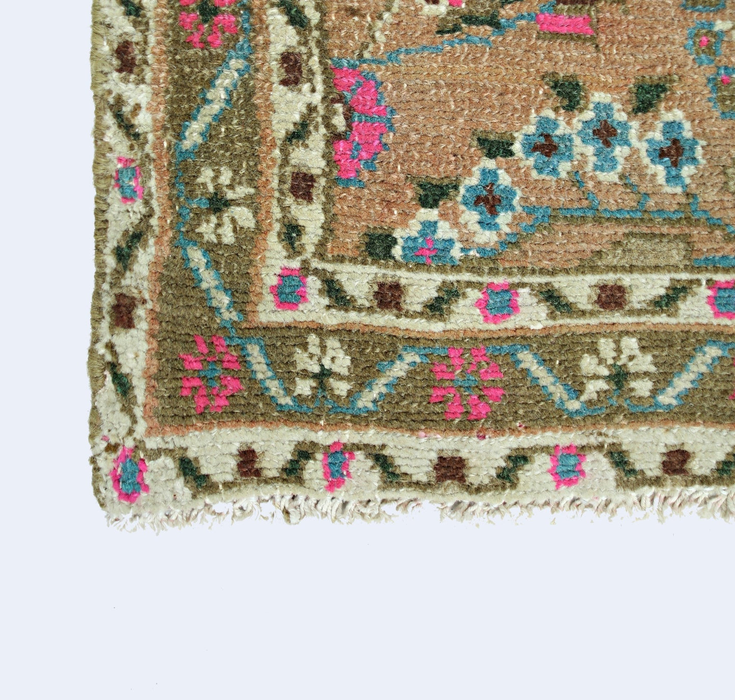 A corner view of a vintage Persian Sarouk rug featuring floral patterns in pink, blue, and brown.