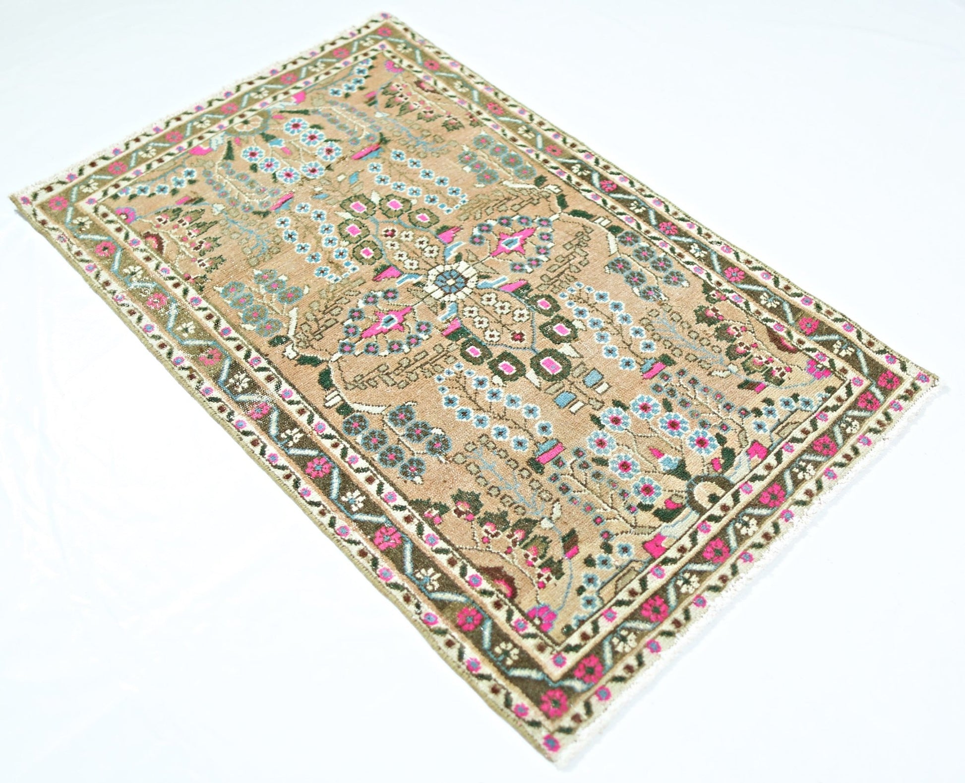 A vintage Persian Sarouk rug featuring a floral pattern in pink, blue, and green on a tan field.