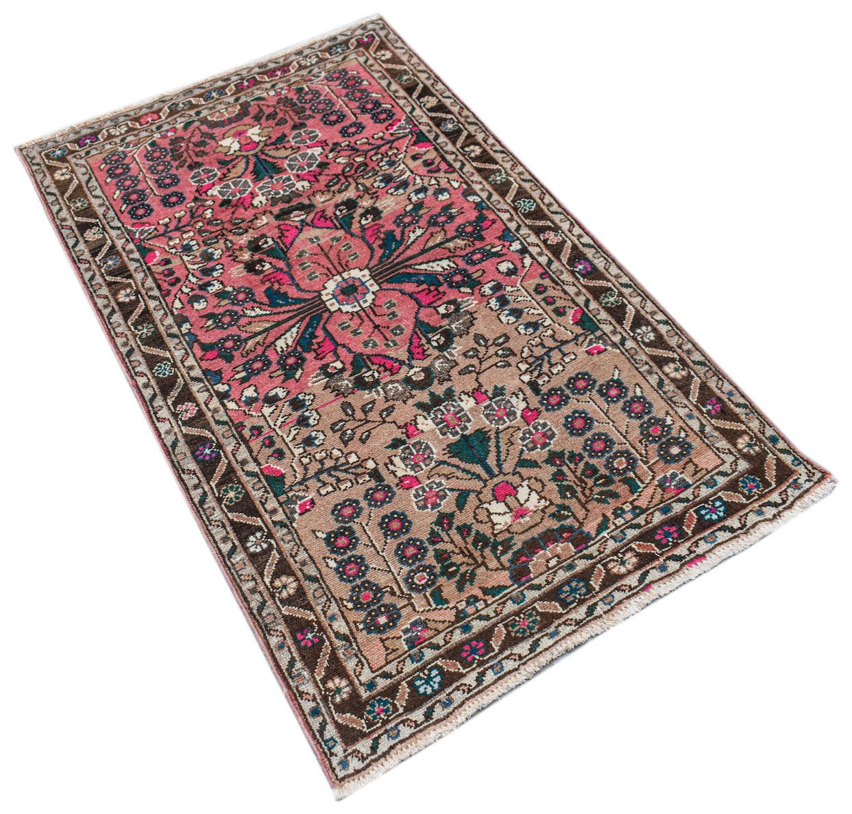 A vintage Persian Sarouk rug featuring a floral pattern in pink, brown, and teal tones.