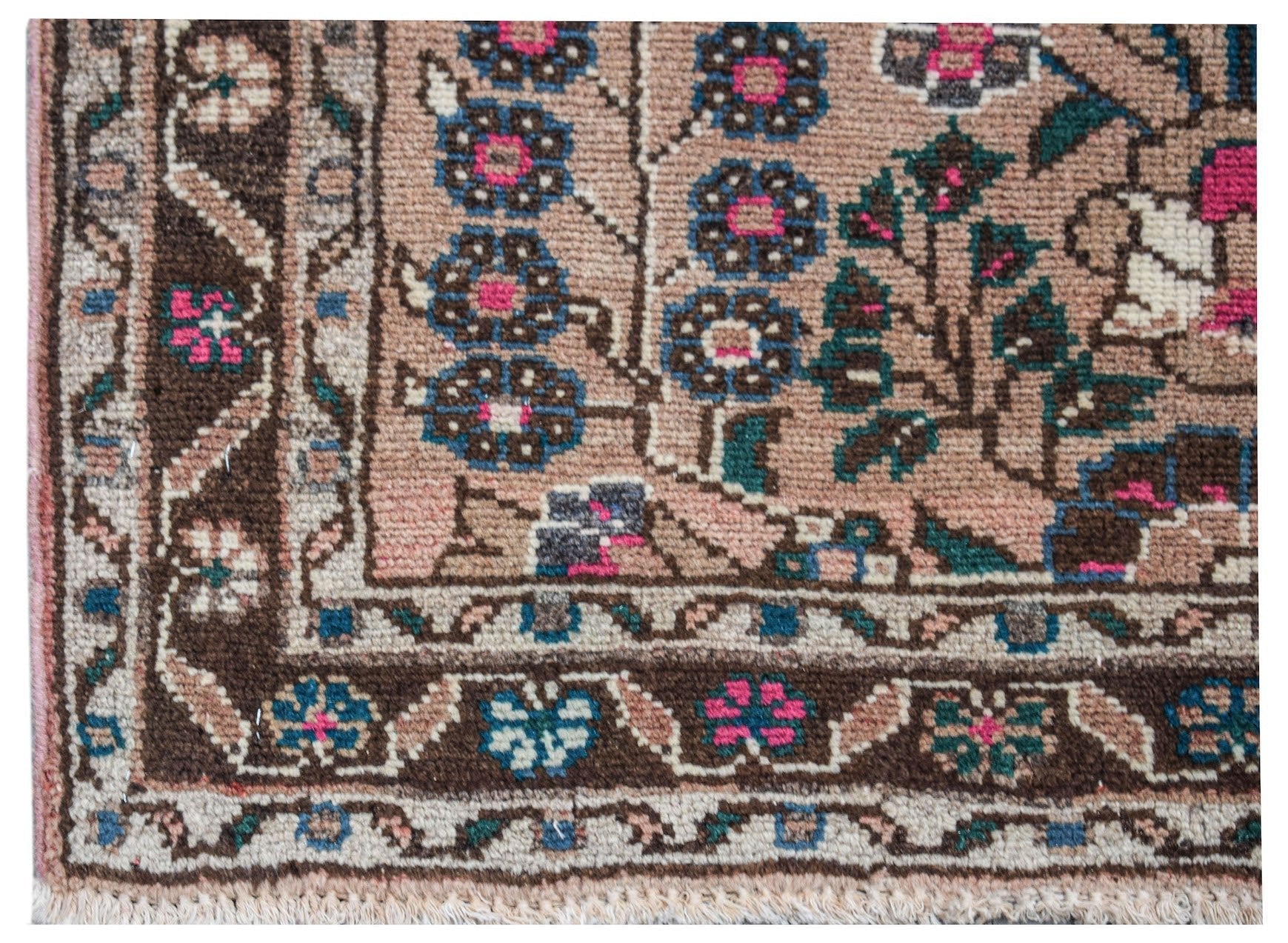A close-up of a vintage Persian Sarouk rug featuring intricate floral patterns in pink and blue.