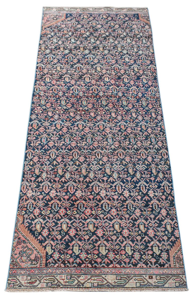 A handwoven vintage Persian Senneh runner featuring a repeating floral pattern in blue and pink.