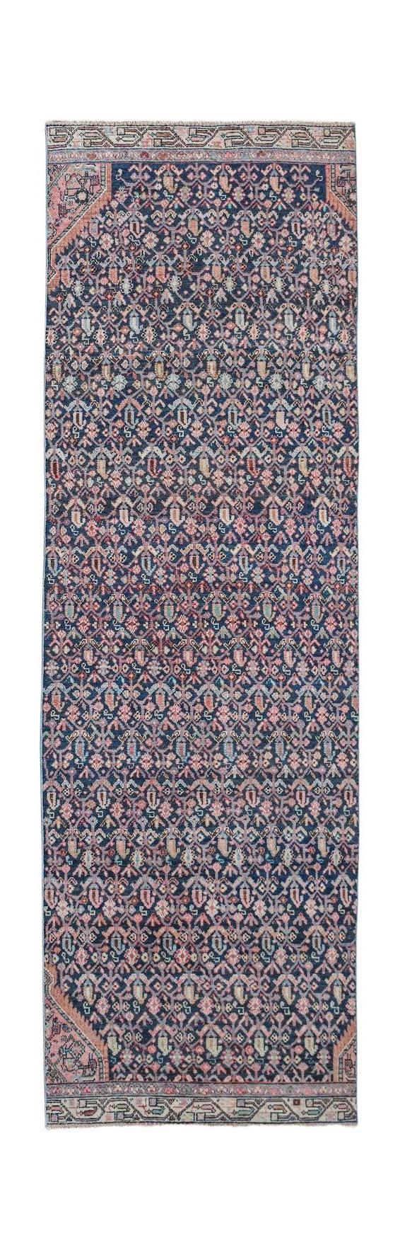 A vintage handwoven Persian Senneh runner featuring a dark blue field with intricate floral motifs.