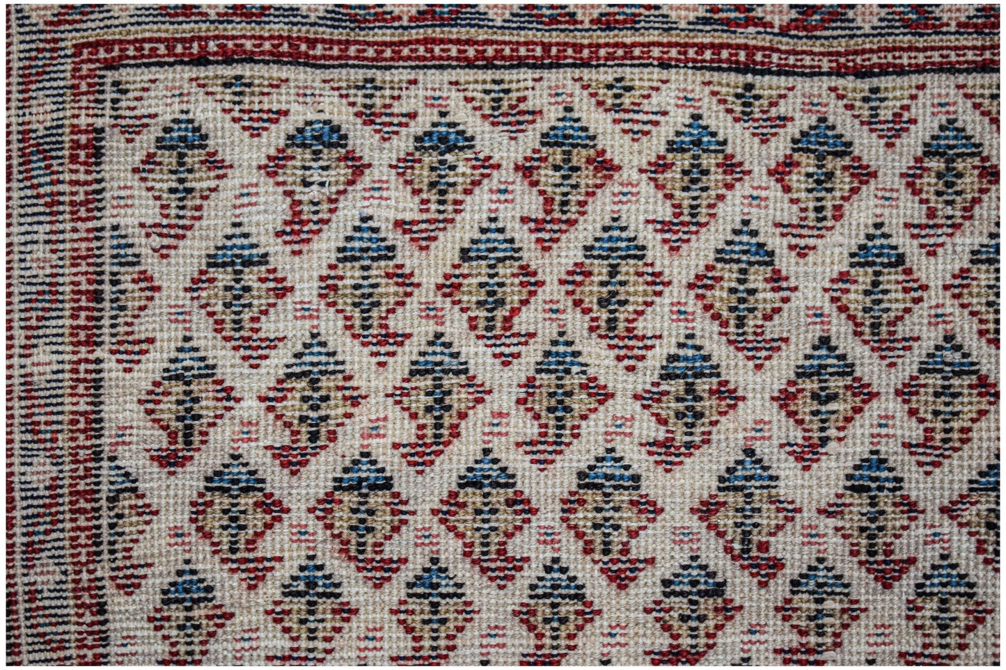 A vintage Persian Saraband rug featuring a repeating blue and tan boteh pattern on a cream field.