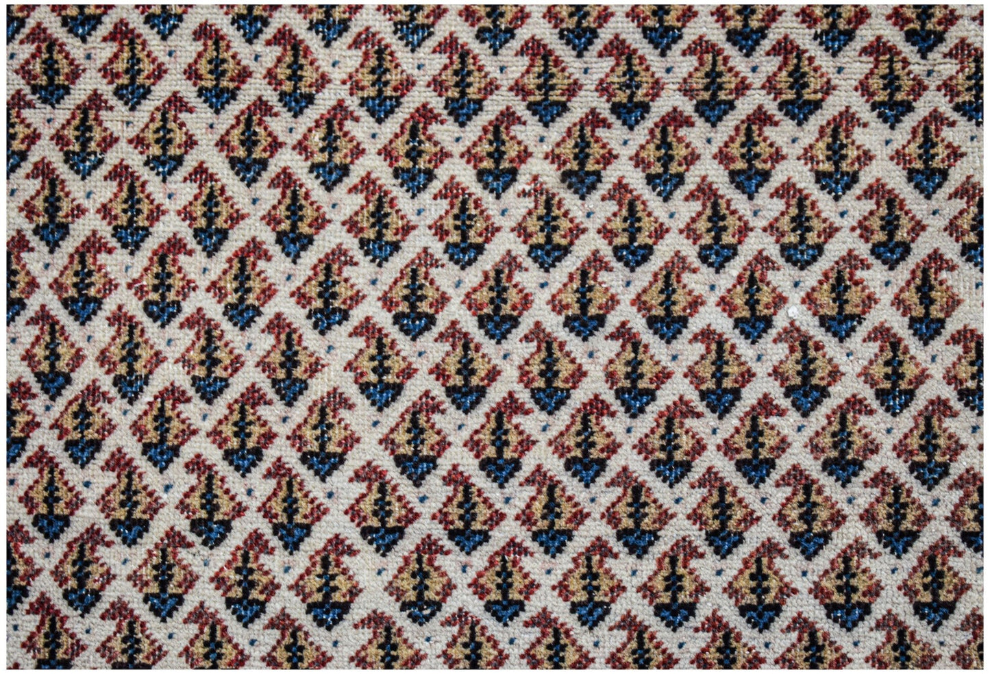 A vintage Persian Saraband rug featuring a repeating blue and red paisley pattern on a cream base.