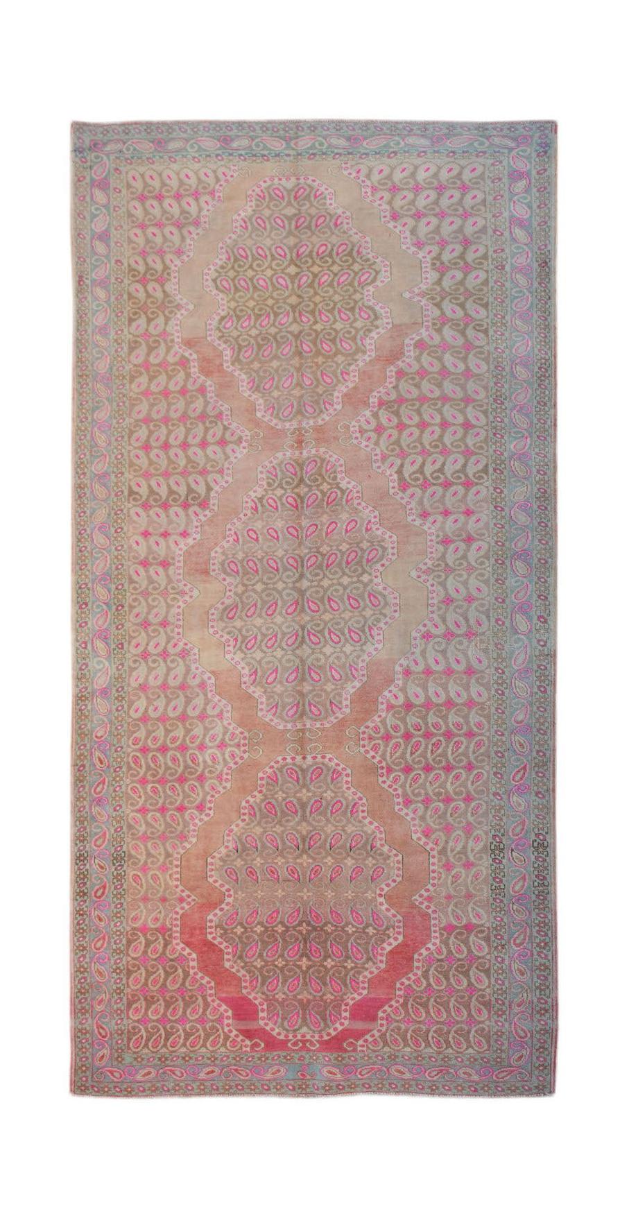 A vintage Persian Senneh rug featuring a repeating paisley pattern in pink and tan tones.