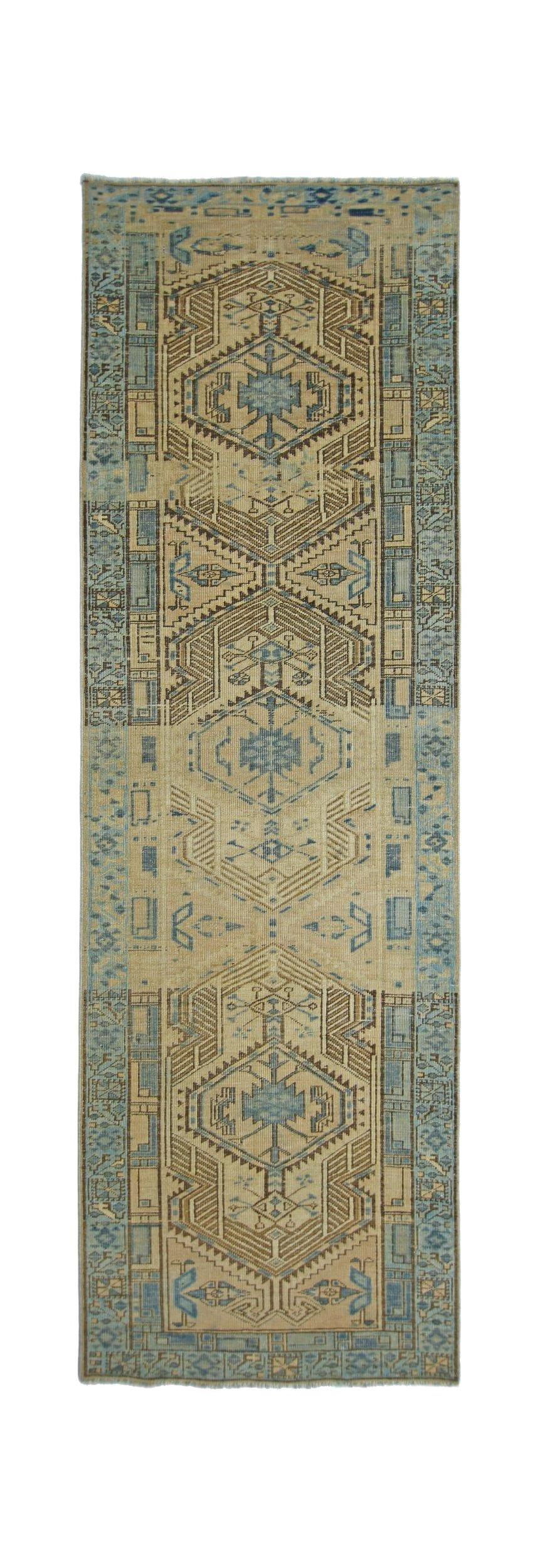 A vintage Persian Serab runner featuring geometric medallions in blue and tan tones.