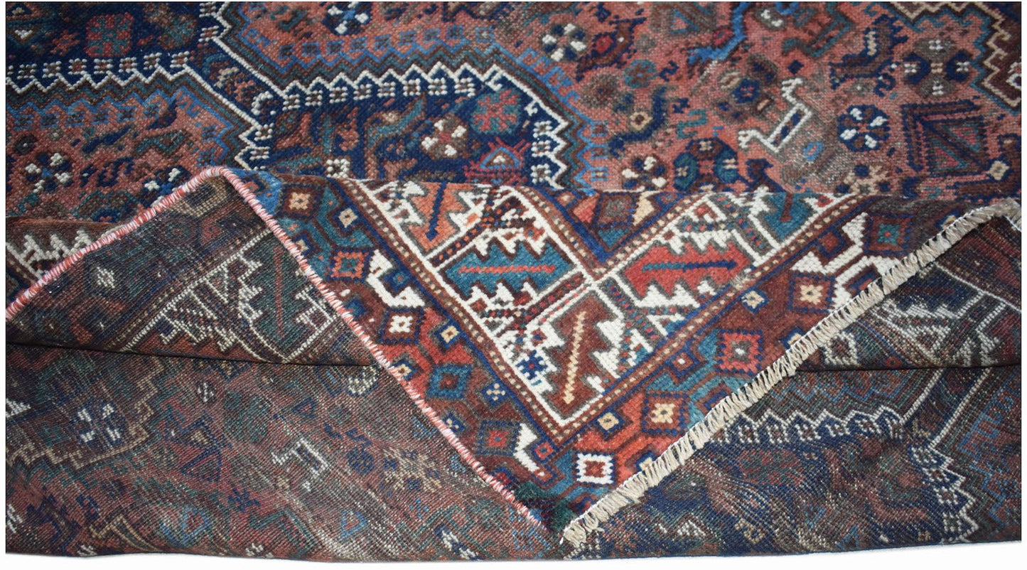 A vintage handwoven Persian Shiraz rug featuring intricate geometric patterns in red and blue wool.