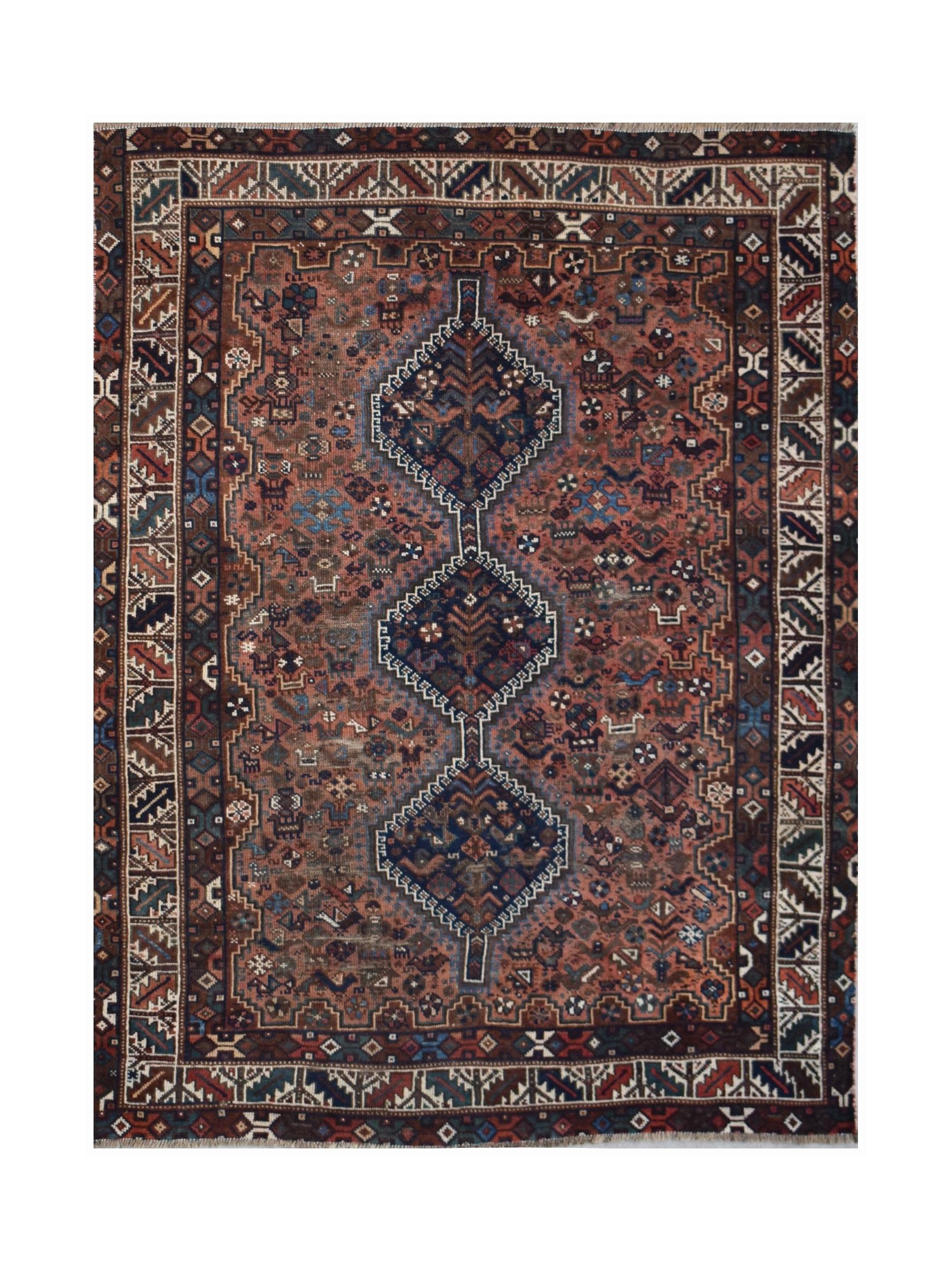 A handwoven vintage Persian Shiraz rug featuring three dark blue diamond medallions on a red field.