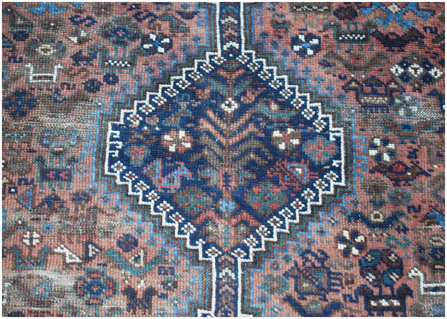 A vintage handwoven Persian Shiraz rug featuring a central blue diamond medallion on a red field.