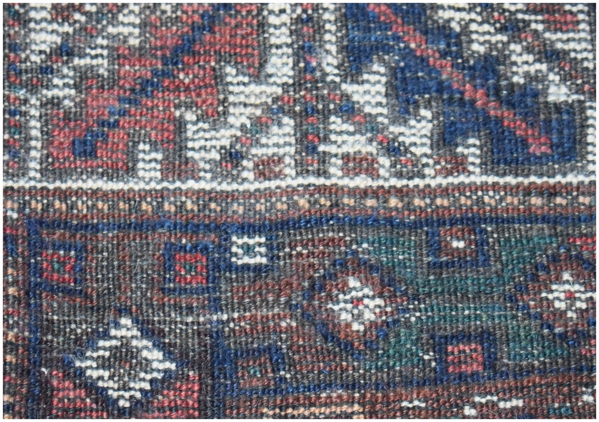 A close-up of a vintage Persian Shiraz rug featuring intricate geometric patterns in wool.