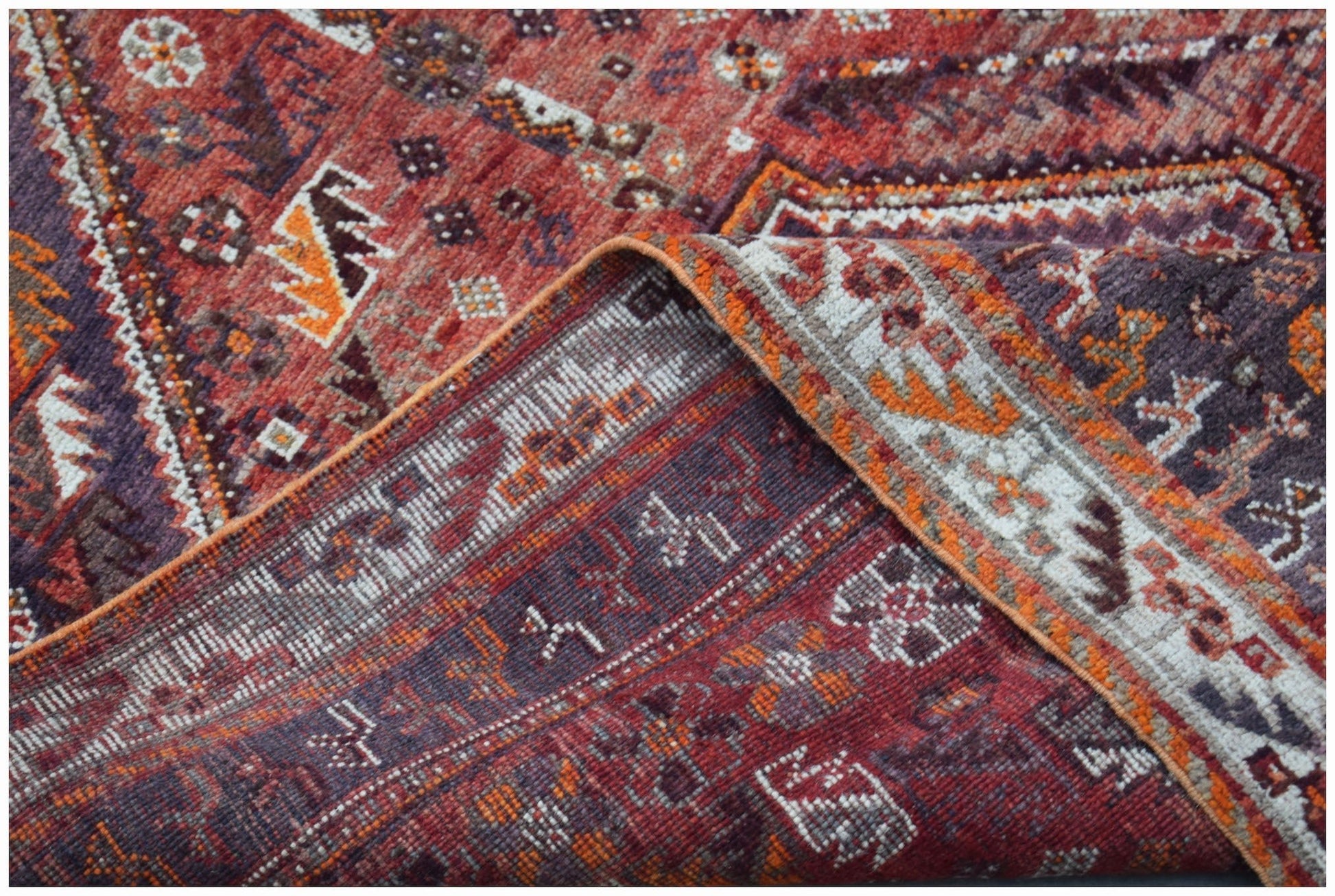 A handwoven vintage Persian Shiraz rug featuring intricate geometric patterns in red and orange.
