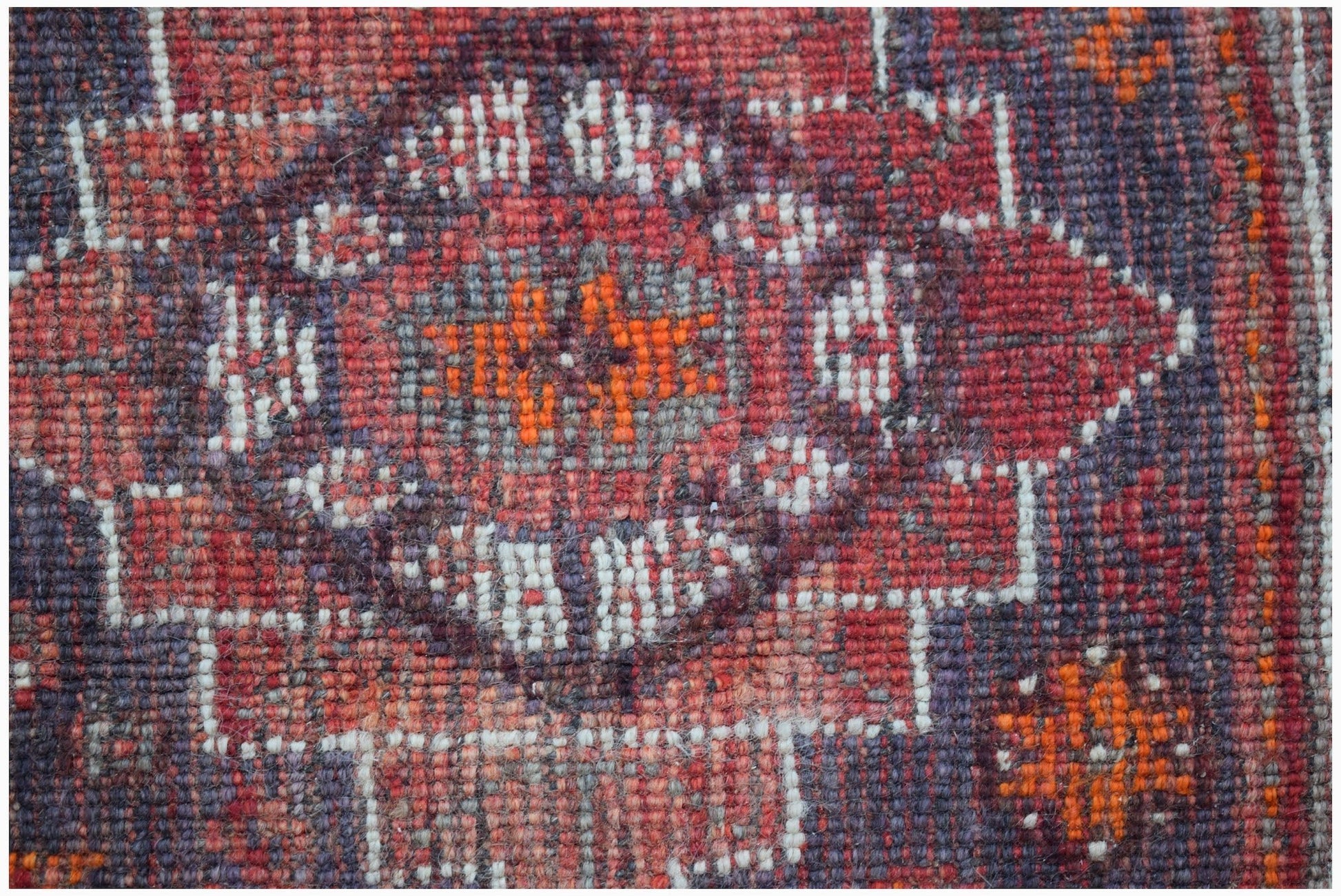 A close-up of a handwoven vintage Persian Shiraz rug featuring a geometric floral medallion.