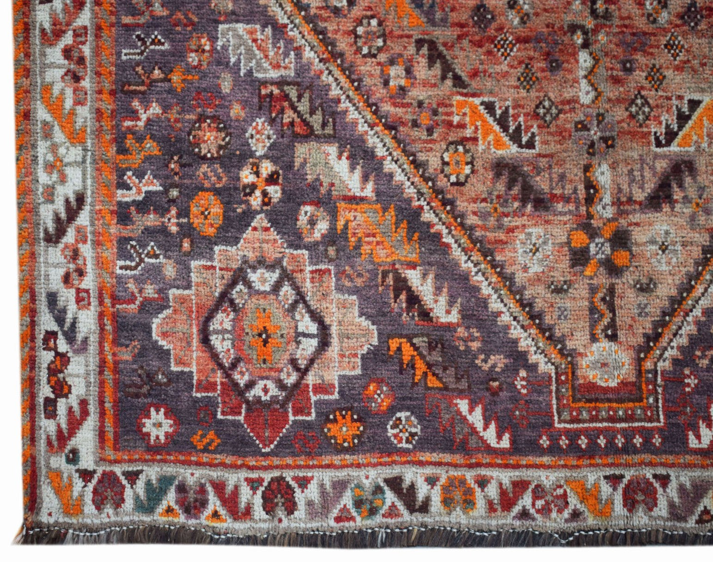 A vintage Persian Shiraz rug featuring a geometric medallion pattern in shades of purple and orange.