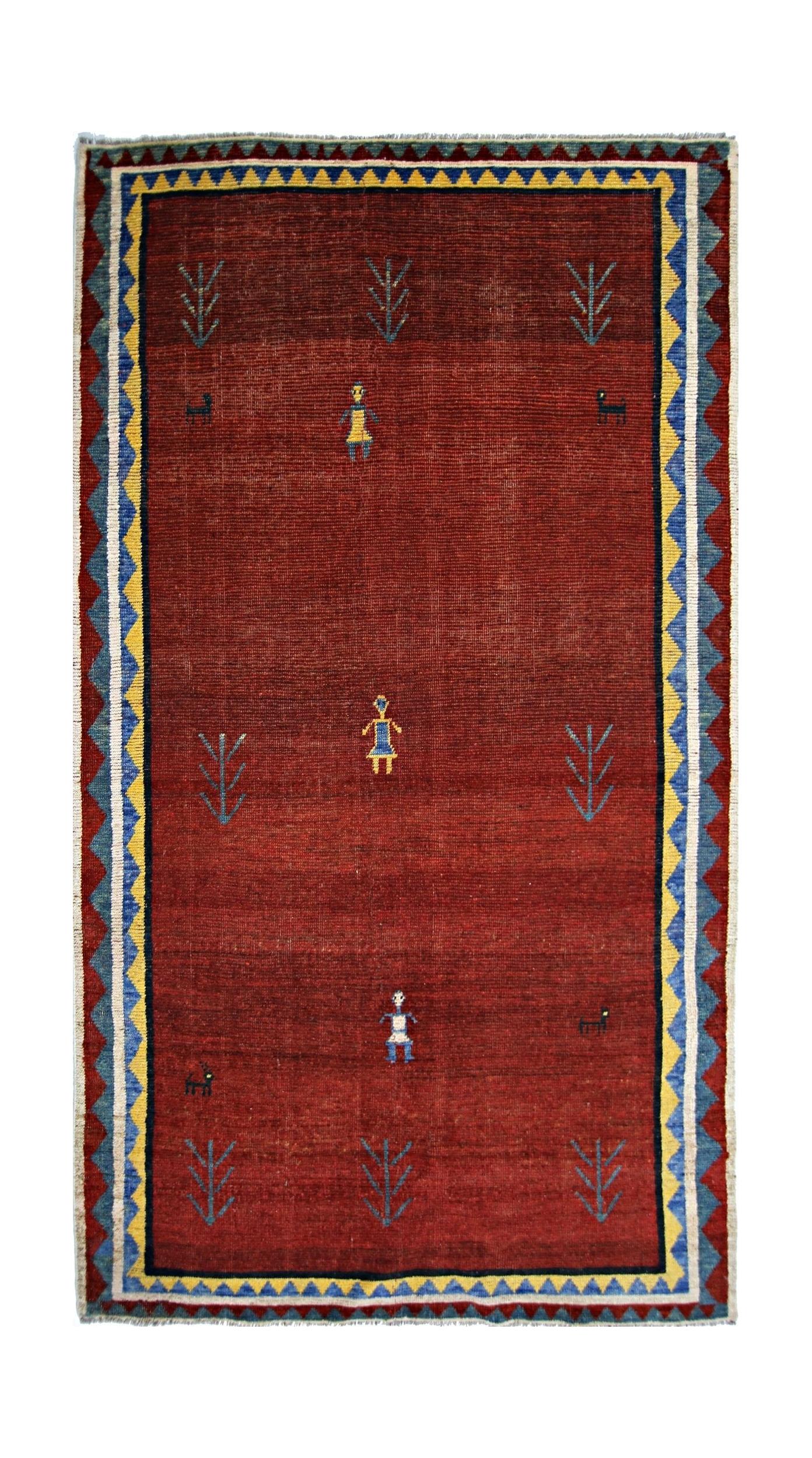 A vintage Persian Shiraz rug featuring a deep red field with stylized figures and tree motifs.