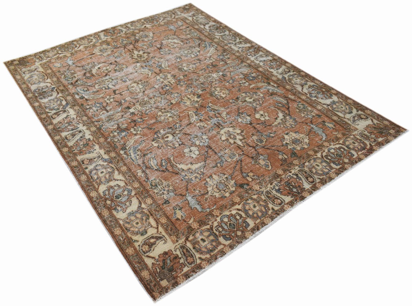 A vintage Persian Tabriz rug featuring a distressed floral pattern in shades of rust and blue.