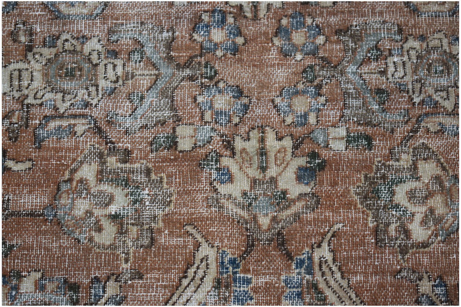 A vintage Persian Tabriz rug featuring a distressed floral pattern in rust, blue, and cream tones.