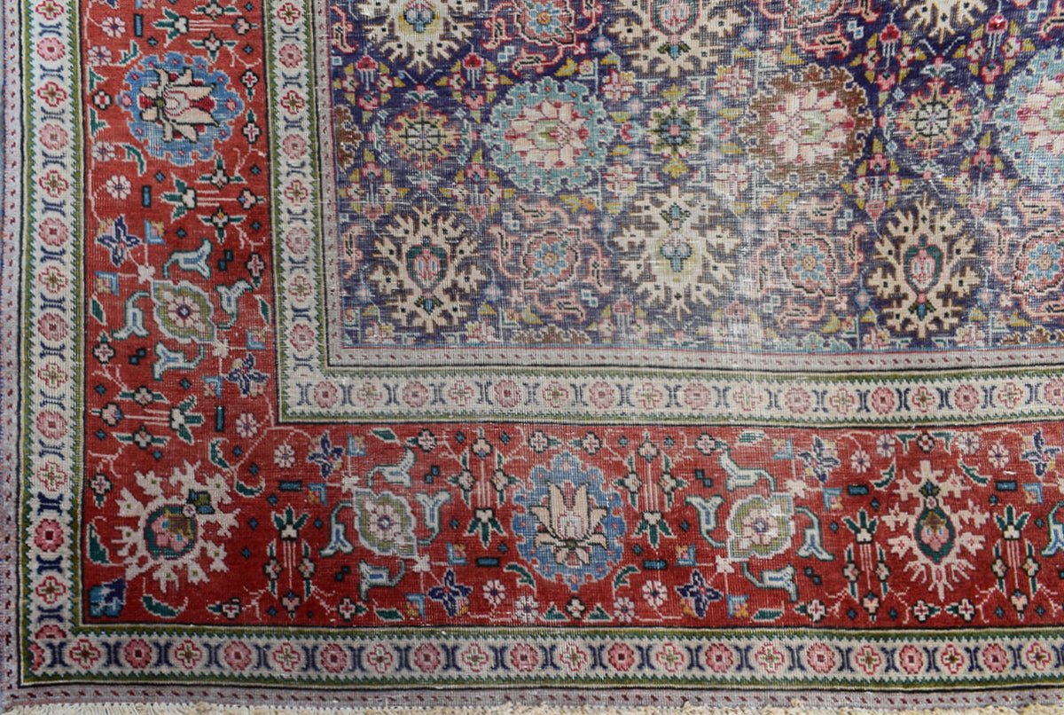 A vintage handwoven Persian Tabriz rug featuring intricate floral patterns in red and blue tones.