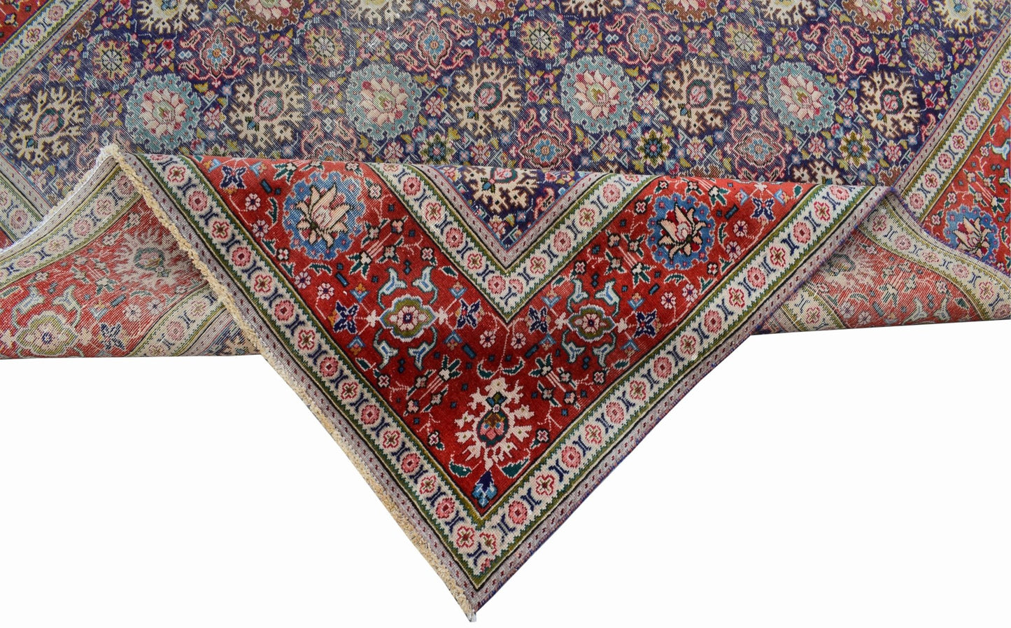 A vintage handwoven Persian Tabriz rug featuring intricate floral patterns in red and blue tones.