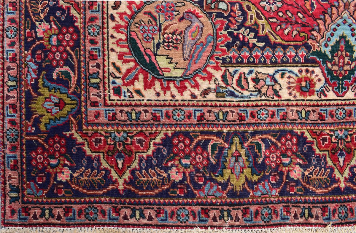 A vintage Persian Tabriz rug featuring an intricate floral medallion and detailed border patterns.