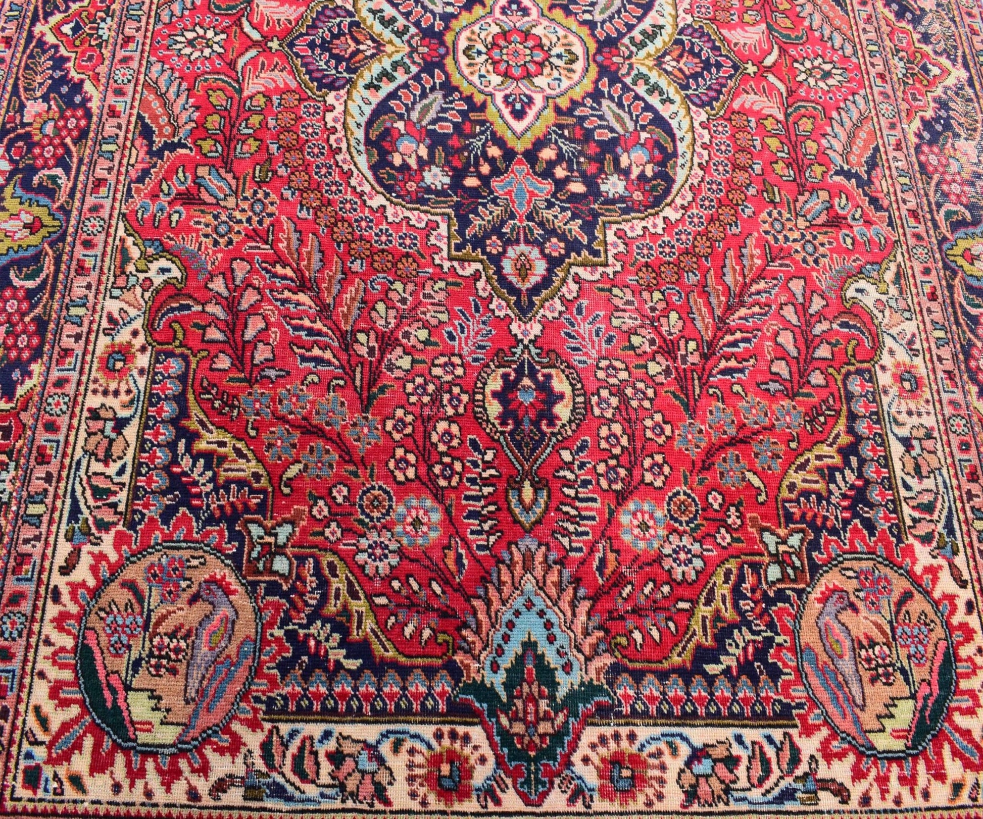 A vintage Persian Tabriz rug featuring an intricate floral medallion design in red and blue tones.