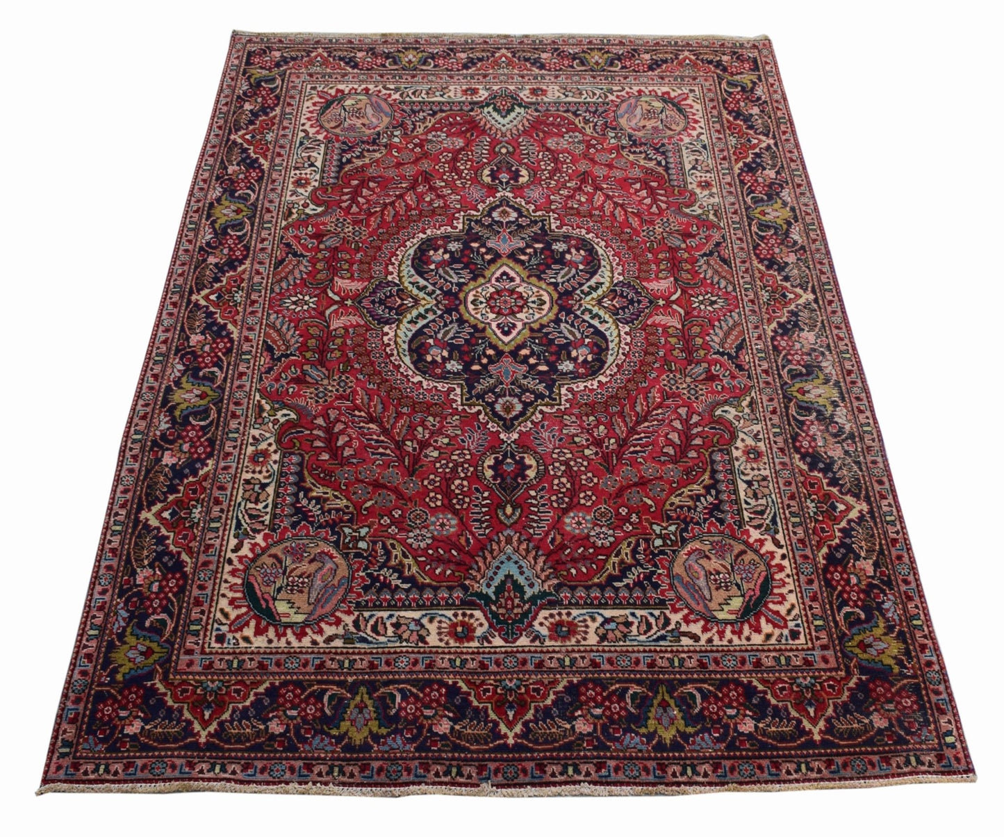 A vintage Persian Tabriz rug featuring a central medallion and intricate floral patterns in red.
