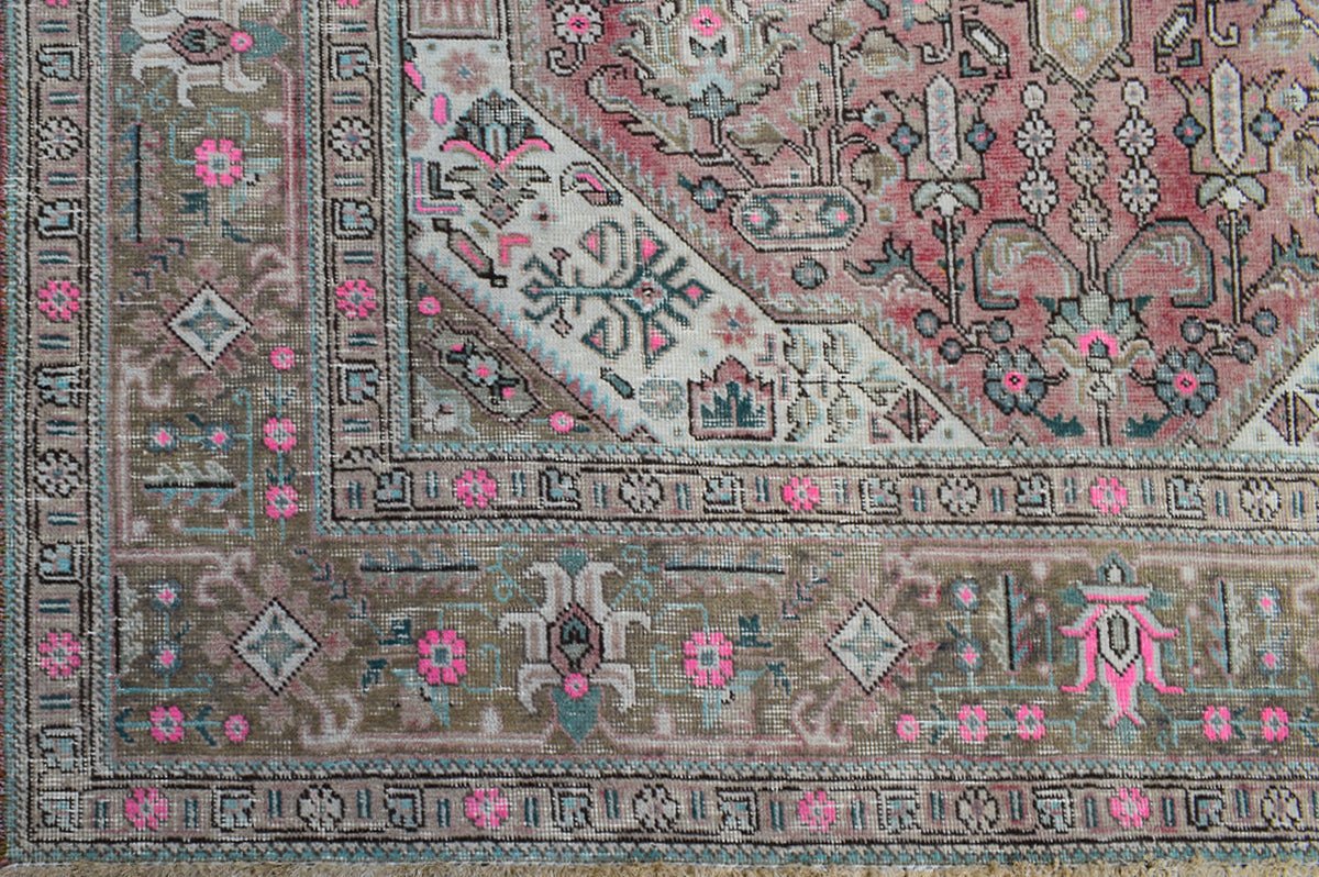 A vintage handwoven Persian Tabriz rug featuring intricate floral patterns in pink and muted tones.