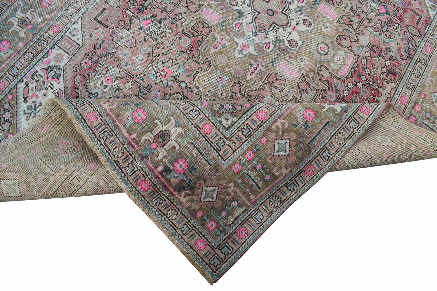 A vintage Persian Tabriz rug featuring intricate floral patterns in muted tones with pink accents.