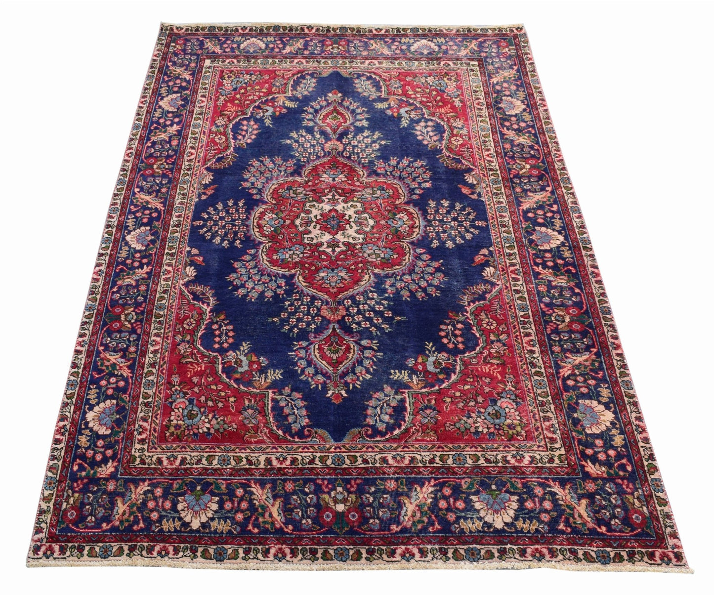 A vintage Persian Tabriz rug featuring a central medallion and intricate floral patterns in blue.