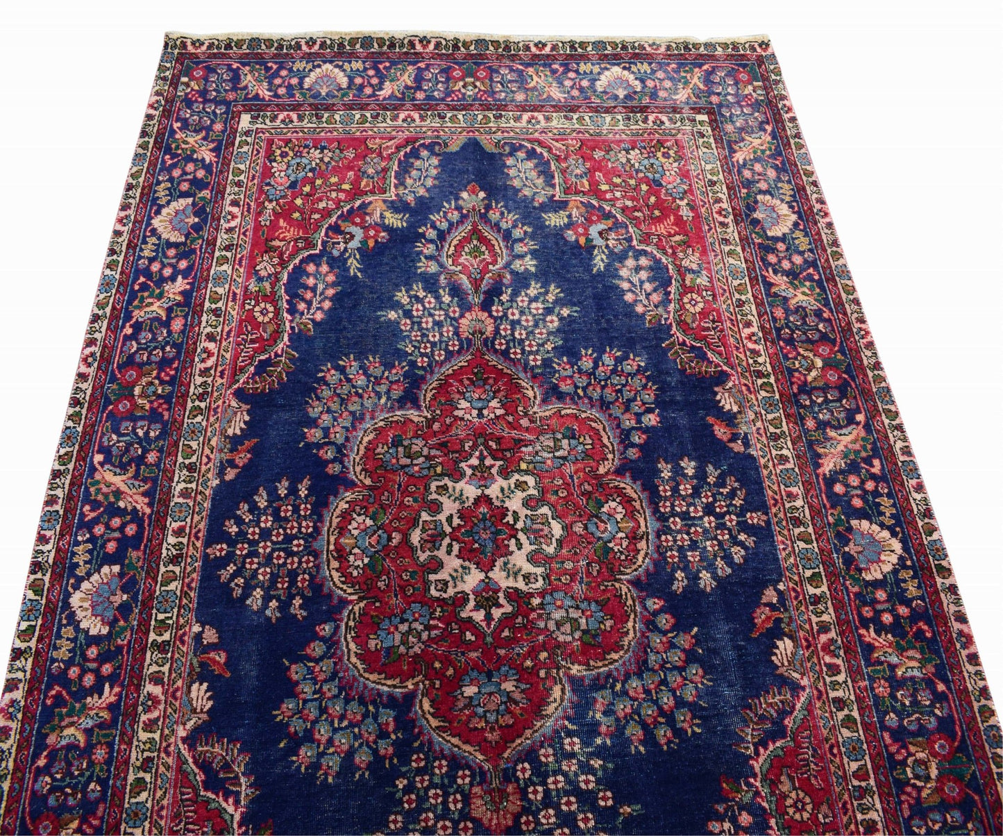 A vintage Persian Tabriz rug featuring a central red medallion on a deep blue floral field.