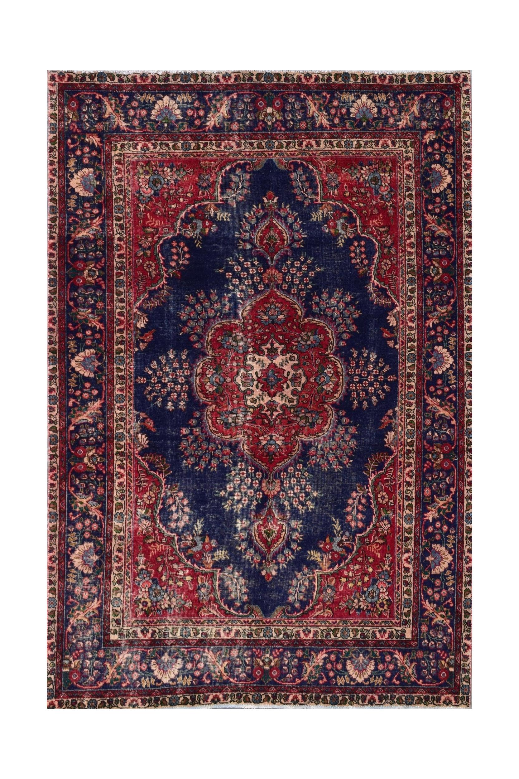 A vintage Persian Tabriz rug featuring a central floral medallion on a deep blue field.