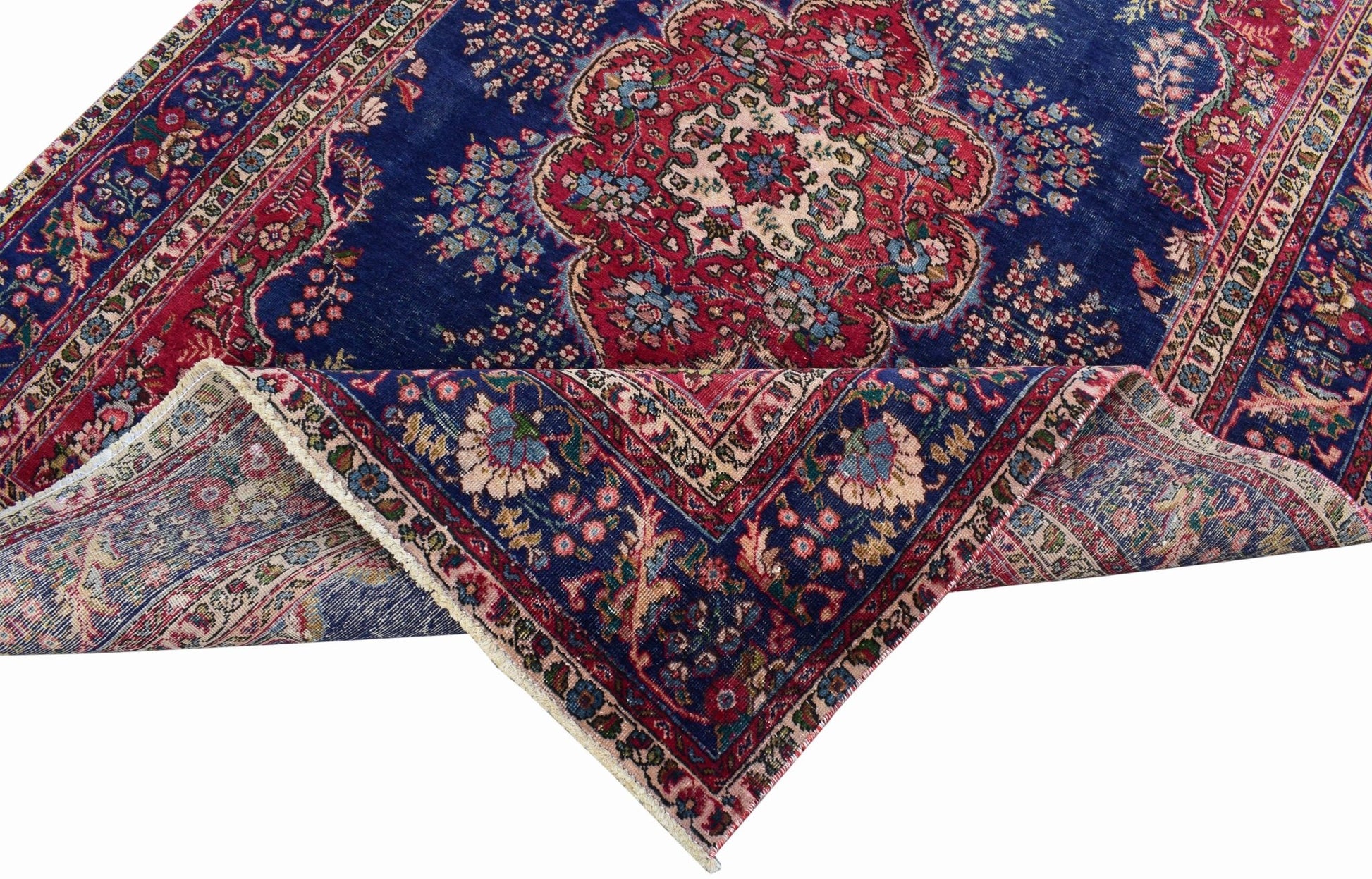 A vintage Persian Tabriz rug featuring a central floral medallion on a deep blue field.