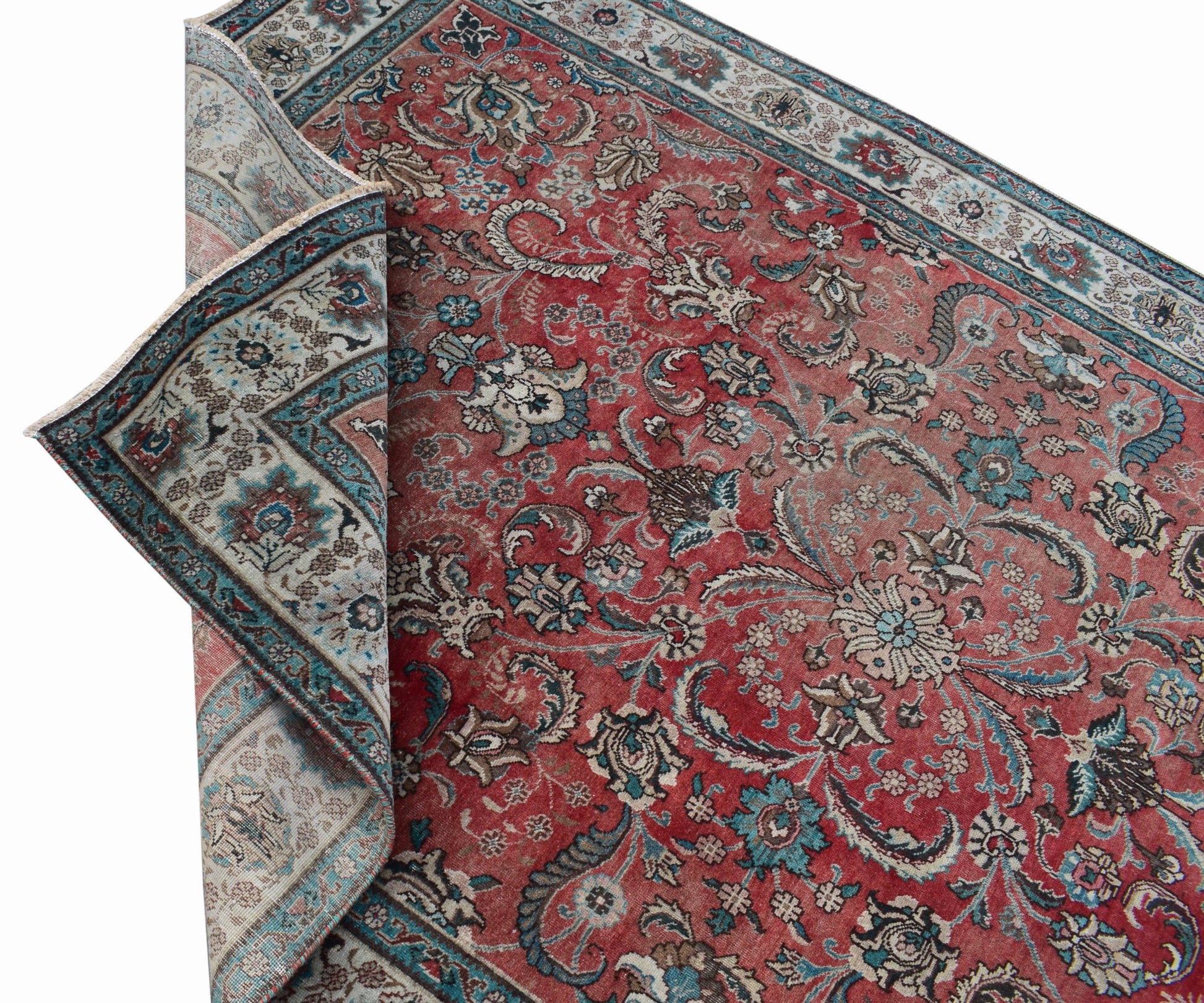 A vintage Persian Tabriz rug featuring an intricate floral pattern in red, blue, and cream tones.