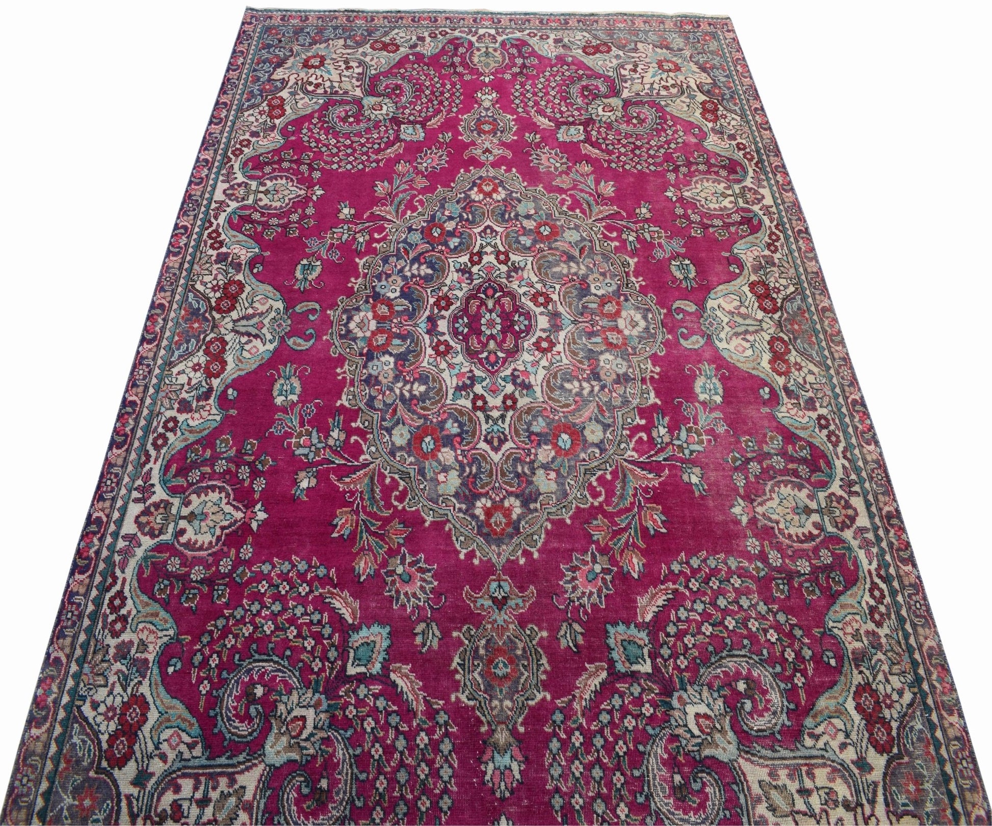 A vintage Persian Tabriz rug featuring an intricate floral medallion design in shades of magenta.