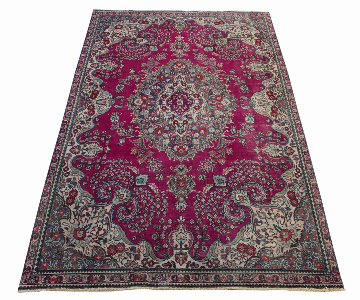 A vintage Persian Tabriz rug featuring an intricate floral medallion on a deep magenta field.