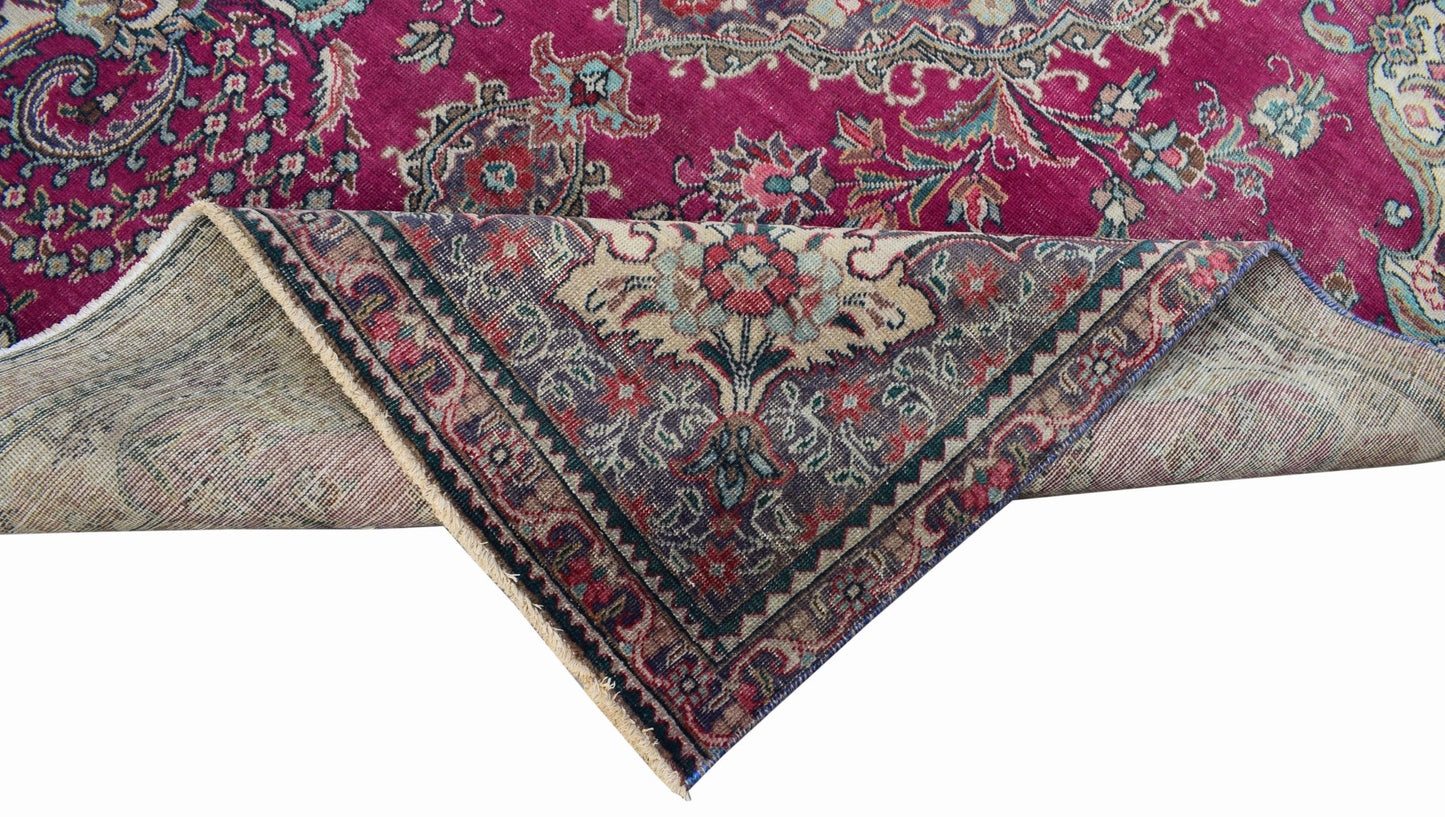 A vintage Persian Tabriz rug with a vibrant magenta field and intricate floral medallion patterns.