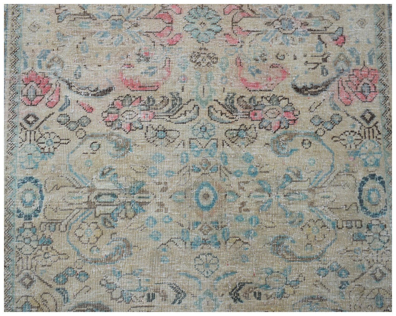 A vintage handwoven Persian Tabriz rug featuring a faded floral pattern in blue, pink, and beige.
