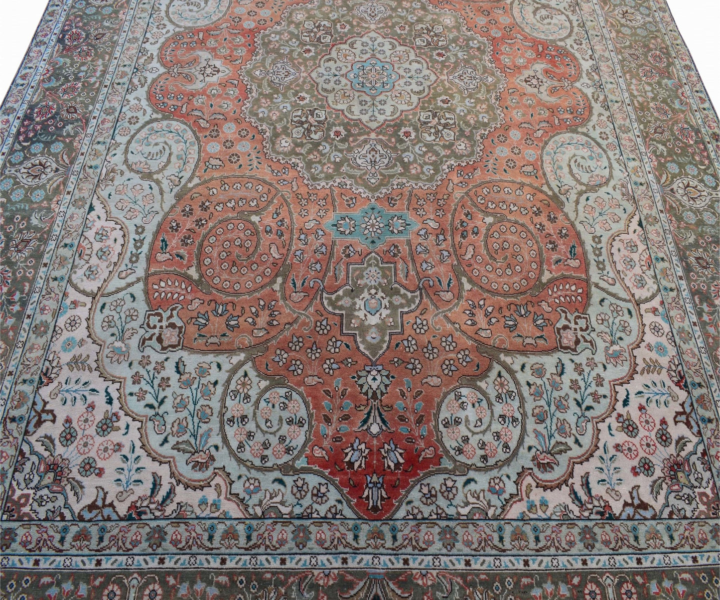 A vintage Persian Tabriz rug featuring intricate floral patterns in shades of orange and sage green.