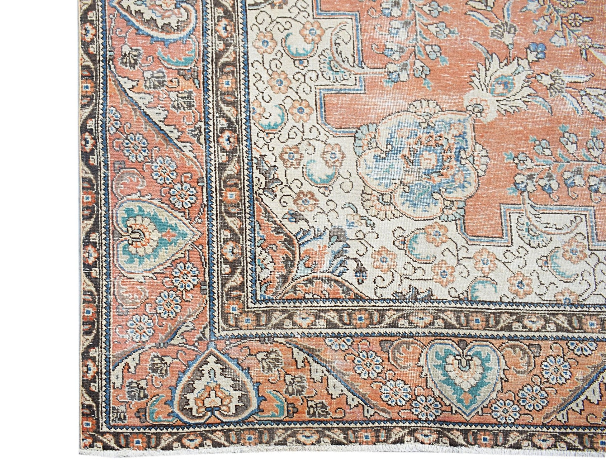 A vintage Persian Tabriz rug featuring intricate floral patterns in shades of orange and blue.