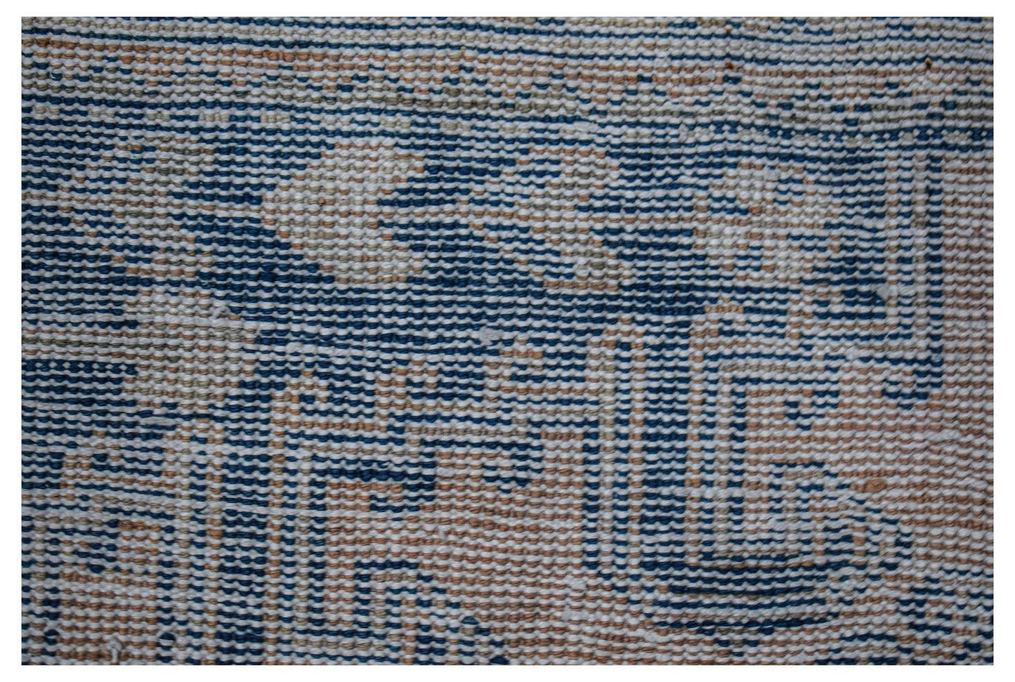A close-up of a vintage Persian wool rug featuring a faded blue and beige geometric pattern.