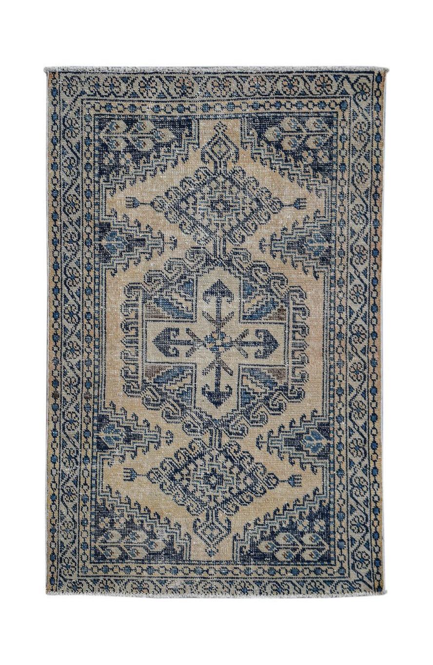 A vintage handwoven Persian rug featuring a blue and beige geometric medallion pattern.